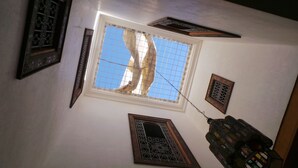 Una habitación con techo alto, un amplio ventanal con diseño de cuadrícula y varios paneles decorativos en la pared.
