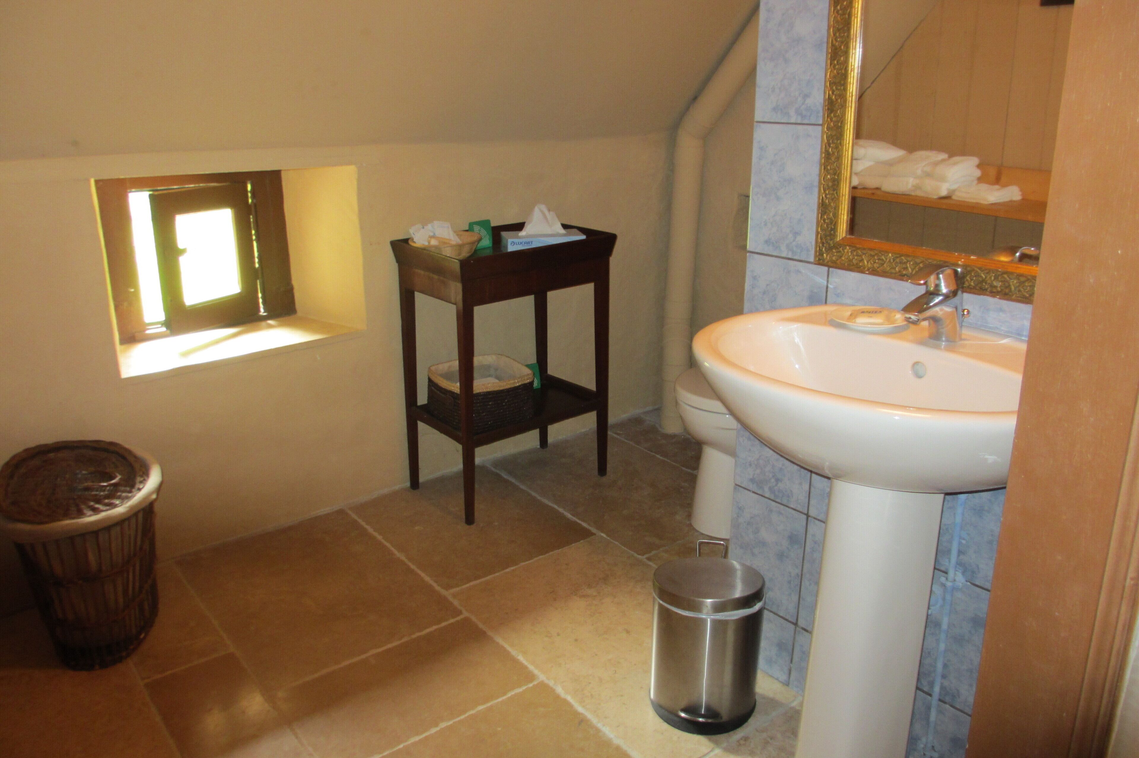 A bathroom with a sink, mirror, and window.