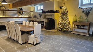 Un coin repas avec une table et des chaises en bois, un sapin de Noël et une cheminée.