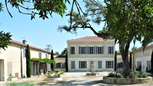 Une cour intérieure avec une fontaine centrale, entourée de bâtiments à l’architecture traditionnelle, sous un ciel dégagé.