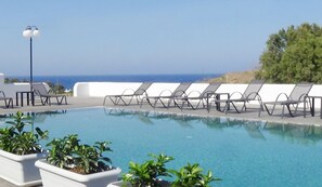 Un espace piscine aménagé avec des chaises longues et des plantes en pot.