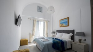 A modern bedroom with a bed, bedside tables, a TV, and a painting. - 3 bedroom Luxury villa , 200m by  famous Monolithos  beach!  (Έξω Γιαλός Καρτεραδου)