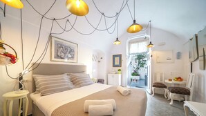 Ein Schlafzimmer mit Bett, Nachttisch, Lampe und Blick ins Freie.