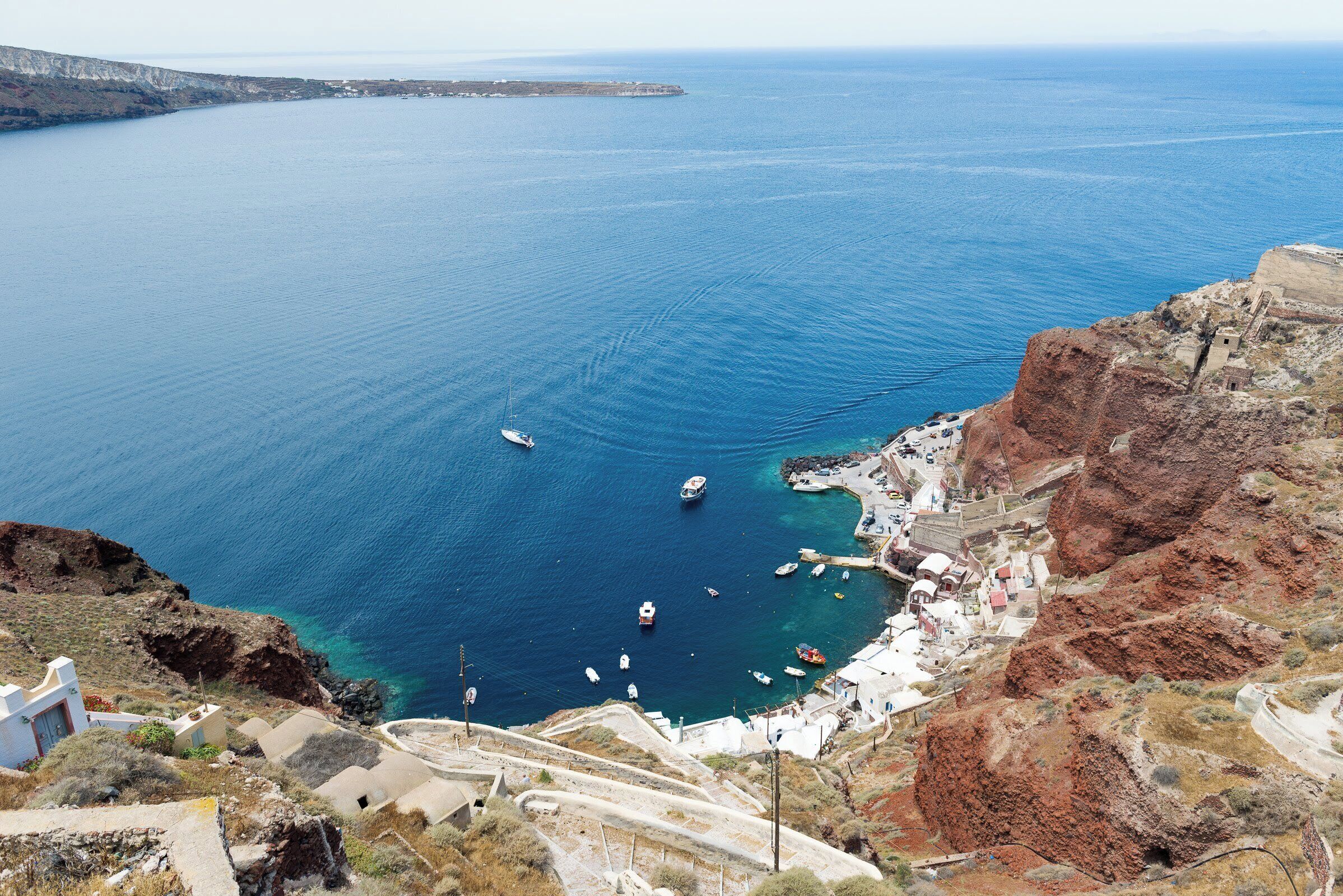 A coastal village with a clear view of the sea, boats, and rugged cliffs.