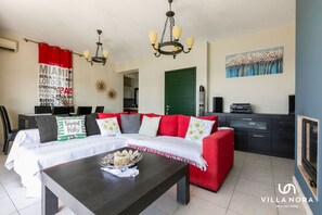 A modern living room with a red sofa, a dark wooden coffee table, and a chandelier.