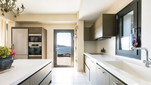 A modern kitchen with a view to the sea, a built-in oven, and a large window.