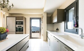 A modern kitchen with a view to the sea, a built-in oven, and a large window.