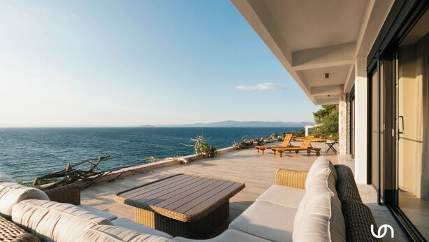 A terrace with wicker furniture, a wooden table, and a view of the sea.