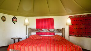 A bed with a red striped bedspread, a wooden headboard, and two wall-mounted lamps.