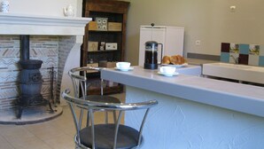 Une cuisine équipée d’une machine à café, de croissants et d’un poêle rustique.
