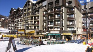 Ein mehrgeschossiges Hotel mit Balkonen, Außenbereich und einer Skipiste im Hintergrund.