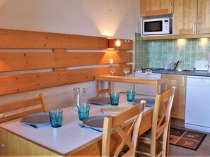 A cozy kitchen with wooden cabinetry, a microwave, and a dining table set with blue glassware and plates.
