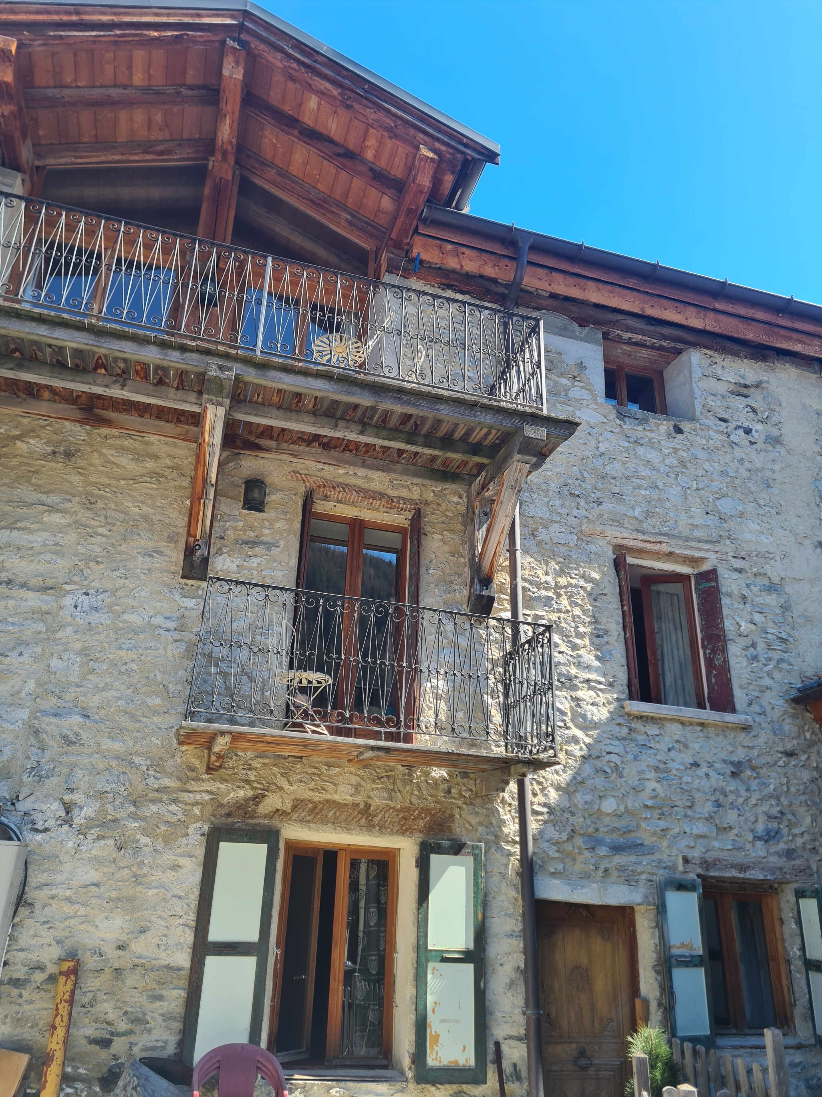 Un bâtiment en pierre doté d’un balcon en bois et d’une fenêtre avec des volets.