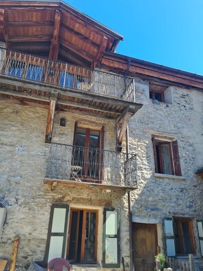A stone building with a wooden balcony and a window with shutters. - Stunning Chalet in Alpine village with 5 bedrooms/5 bathrooms (Peisey-Nancroix)