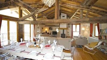 Un espace repas doté d’un plafond en bois, d’un lustre et d’une table mise pour le repas.