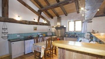 Une cuisine avec des poutres en bois, une table à manger et un évier.