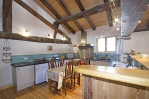 A kitchen with wooden beams, a dining table, and a sink. - Stunning Chalet in Alpine village with 5 bedrooms/5 bathrooms (Peisey-Nancroix)