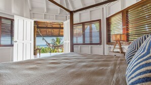 A bedroom with a large bed, wooden beams, a hammock outside, and a view of the sea. - Cliff House with Private Infinity Pool. 3 Minute Walk to the Beach. (Puntarenas)