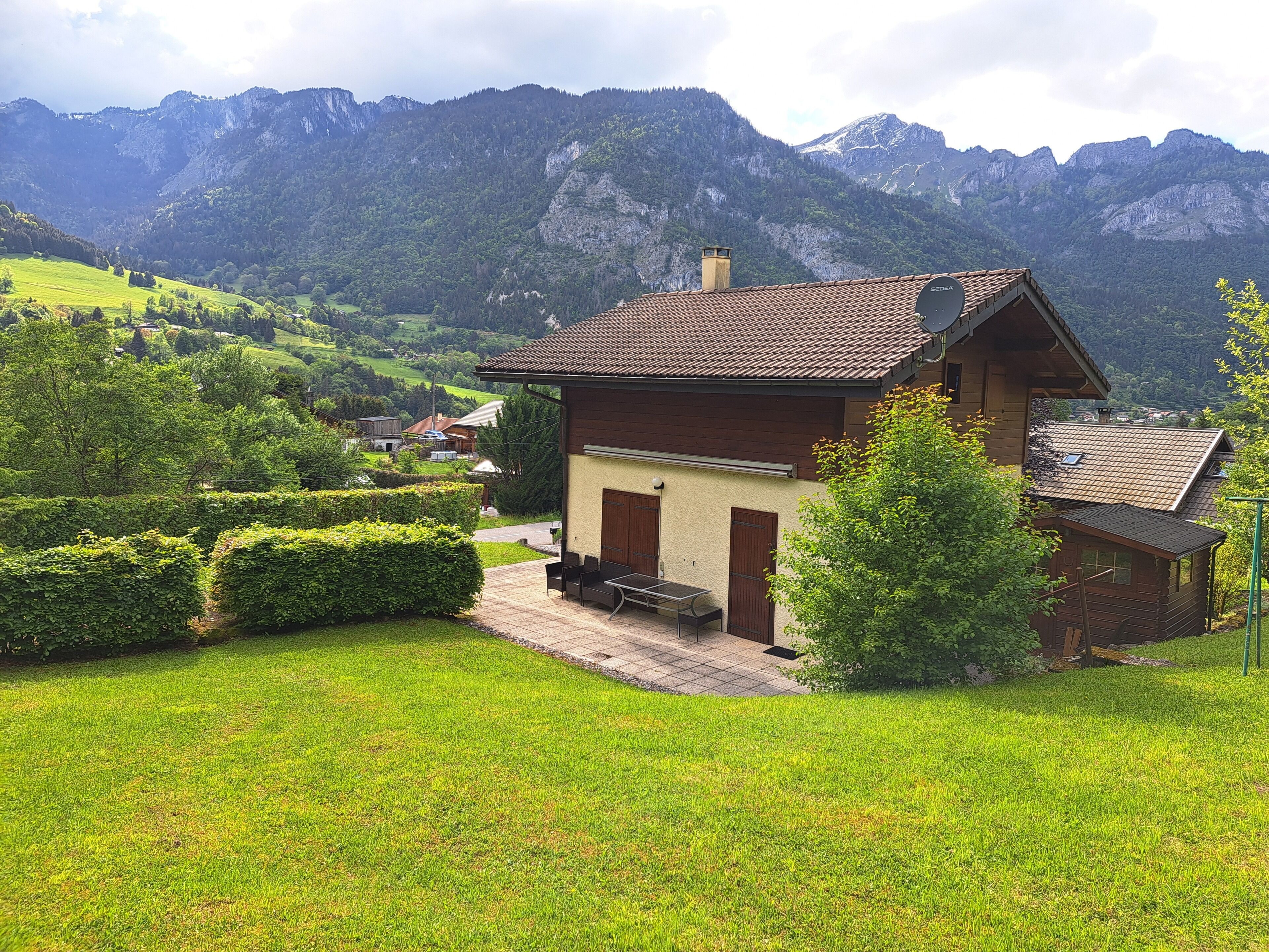 Eine Chalet mit einem geneigten Dach, einer kleinen Veranda und Blick auf eine Berglandschaft.