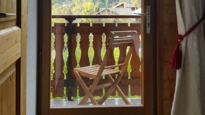 A wooden door with a view of a balcony, a chair, and a mountainous landscape. - Delightful Chalet, village location, garden, parking, views and WiFi (Le Biot)