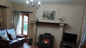 Un salon chaleureux avec une cheminée, un canapé, une table basse et un téléviseur.