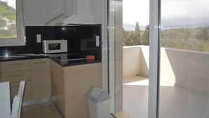 A modern kitchen with a black countertop, a microwave, and a trash bin. - Apartment 80 m2 for 4 people, sea view, swimming pool, parking, washing machine (Kamilari)