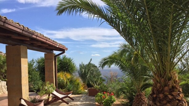 A patio area with lounge chairs, a pergola, and a view of the sea.
