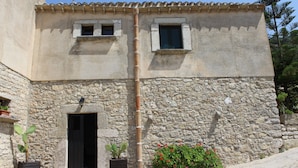 A stone building with a tiled roof, a door, and two windows.