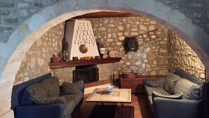 A cozy stone-walled room with a fireplace, two sofas, and a table.