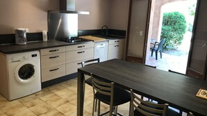 A modern kitchen with a built-in washer, a stove, and a dining area with a table and chairs.
