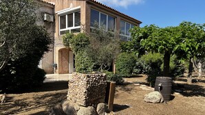 A rustic house with a stone wall, a wooden bench, and a barrel.