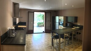 A modern kitchen with a central island, built-in appliances, and a sliding glass door leading to a patio.