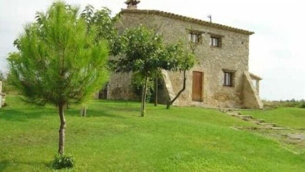 Un edificio de piedra con un pequeño jardín y un árbol en primer plano.