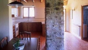 Una cocina rústica con paredes de piedra, armarios de madera y un comedor con mesa y sillas.