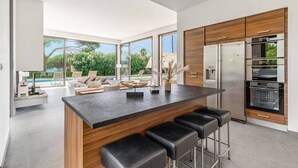 Una cocina moderna con una isla central, taburetes de bar y electrodomésticos integrados.