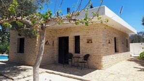 A stone building with a balcony, a table, and chairs. - Villa Elia is situated in a quiet area, surrounded by olive trees with a private (Πιτσίδια)