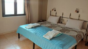 A bedroom with a bed, a window with curtains, an air conditioning unit, and a wall-mounted light fixture. - Villa Elia is situated in a quiet area, surrounded by olive trees with a private (Πιτσίδια)