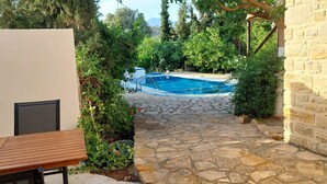 A stone pathway leading to a swimming pool surrounded by greenery. - Villa Elia is situated in a quiet area, surrounded by olive trees with a private (Πιτσίδια)