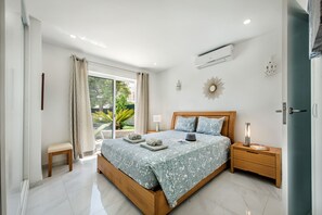 Una camera da letto con un letto grande, un comodino, una finestra con tende e un condizionatore.