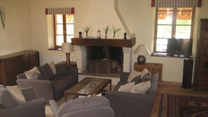 A living room with a fireplace, sofas, a coffee table, and a television.
