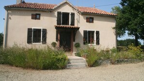 A two-story house with a tiled roof, a front door, and a small porch with steps leading up to it.