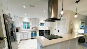 Una cocina moderna con armarios blancos, electrodomésticos de acero inoxidable y una isla central.