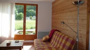 A room with a wooden wall, a sofa, a table, and a floor lamp. - chalet - SAINT LARY SOULAN (Vignec) (VIGNEC)