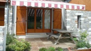 A wooden building with a stone facade, a covered patio with a picnic table, and a small garden area. - chalet - SAINT LARY SOULAN (Vignec) (VIGNEC)