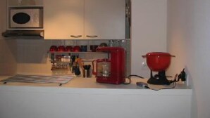 A compact kitchen with white cabinets, a red coffee maker, and a microwave. - chalet - SAINT LARY SOULAN (Vignec) (VIGNEC)