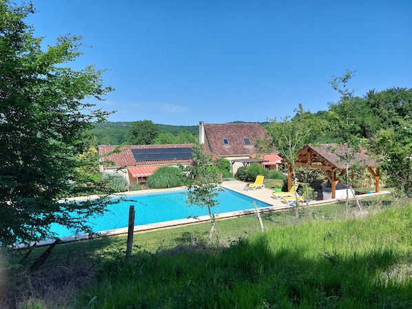 Una casa con piscina, pérgola y jardín.