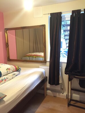 Relax in this serene bedroom with a single bed, ornate mirror, and window with dark curtains.