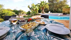 An outdoor dining area with a pool, surrounded by greenery and palm trees. -  Portugal Private Villa with private pool rural quiet tranquil setting (moncaropacho)