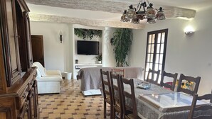 A dining area with a wooden table and chairs, a sofa, and a TV mounted on the wall. - Villa, private swimming pool exclusive to tenants (Cabasse)