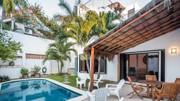 A pool area with a pergola, white lounge chairs, and a dining table. - Swimming Pool, Rooftop Terrace, 4 Blocks from Ocean (Cozumel)